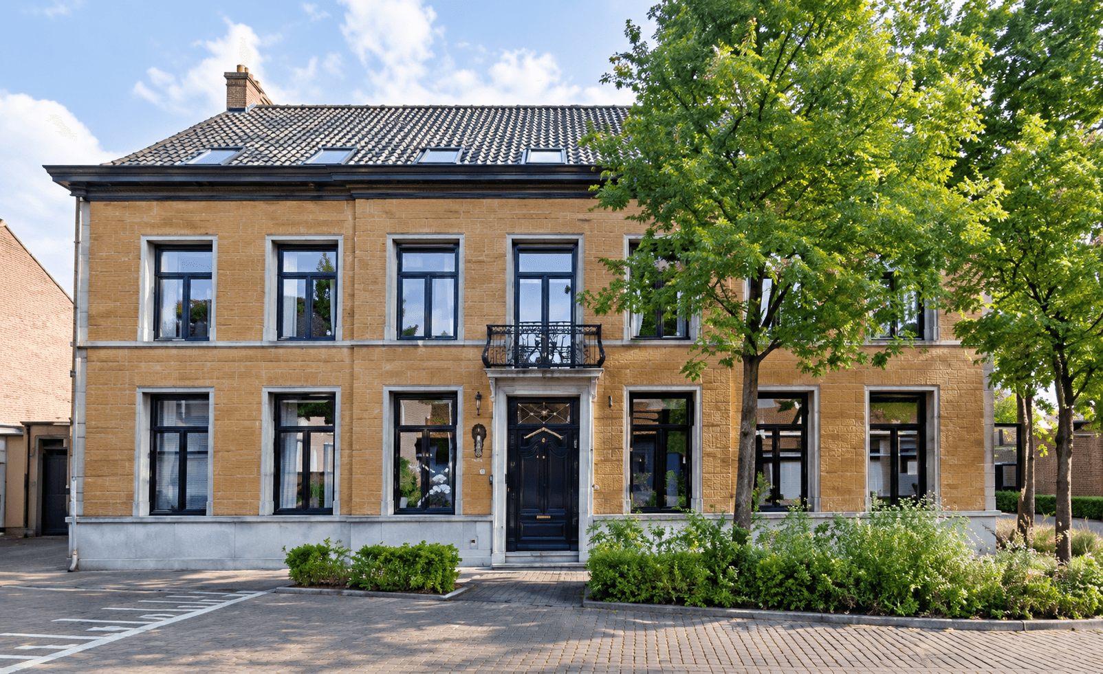 LOTHUUS vandaag: de okerkleurige gevel met donkere ramen, balkon en de boom voor het huis
